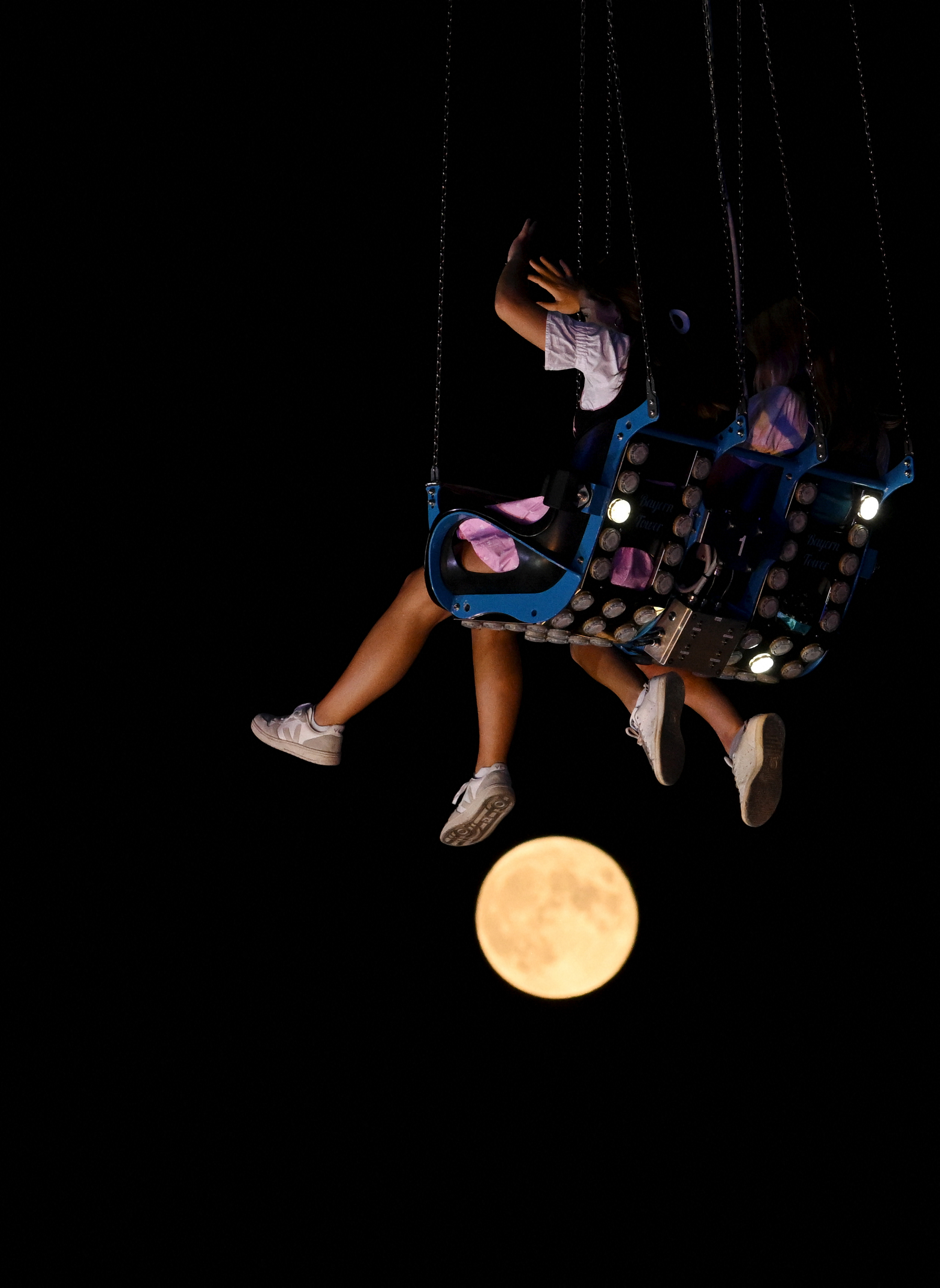 The moon in seen in the background as visitors enjoy their ride in a carousel car