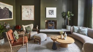 living room with green walls, curved sofa, occasional chairs, coffee tables and log burner inset into wall