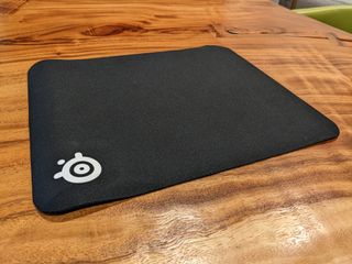 The SteelSeries QcK mouse pad on a wooden table