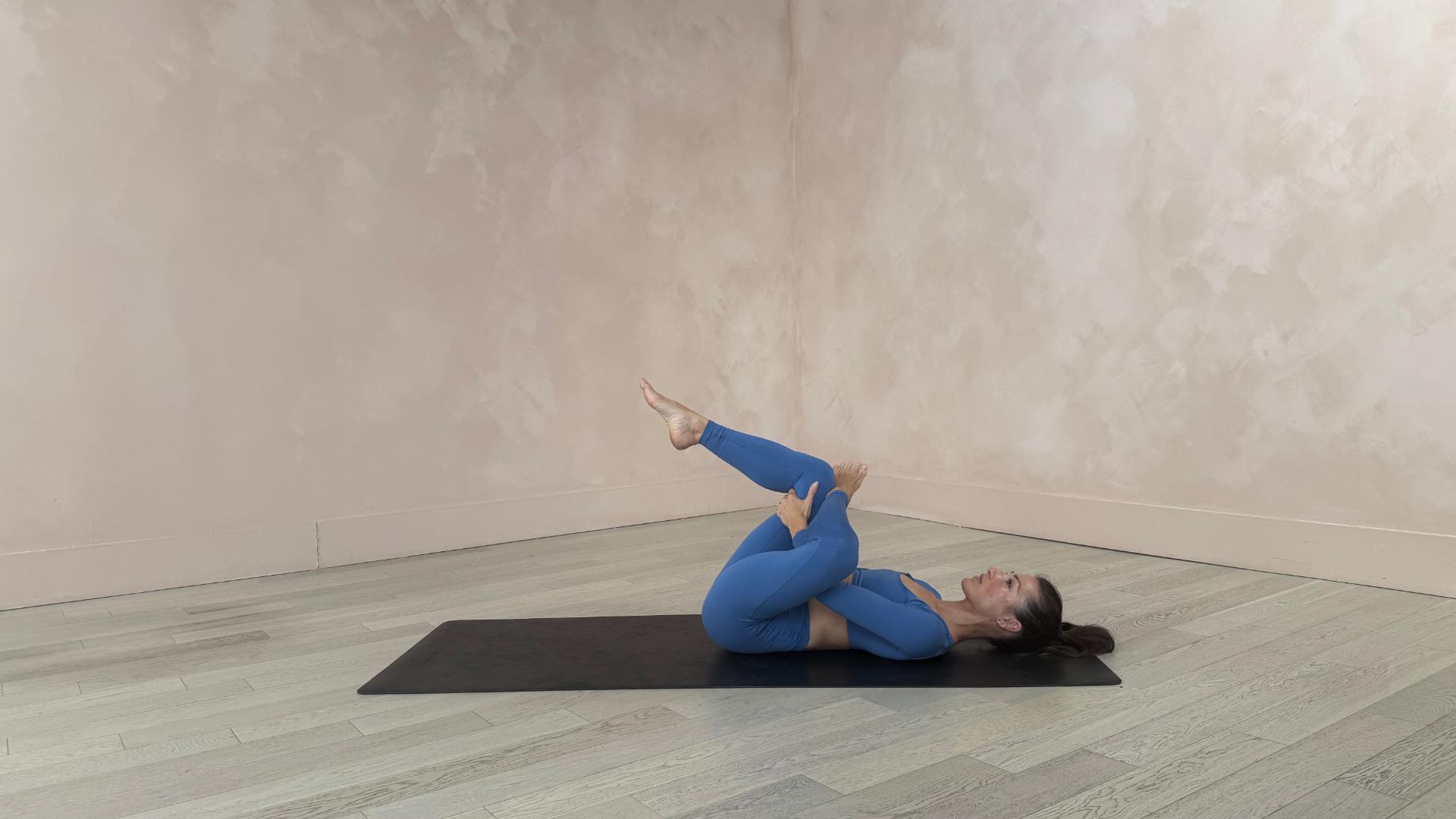 woman stretches on her back on yoga mat