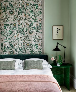 Bedroom accent wall ideas with a pink and green botanical tapestry in a pale green room with pale pink and green accents.
