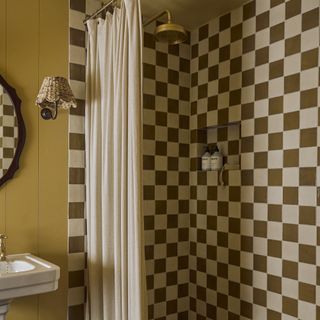 bathroom with brown and white chequerboard tiles in shower and wood panel walls painted yellow