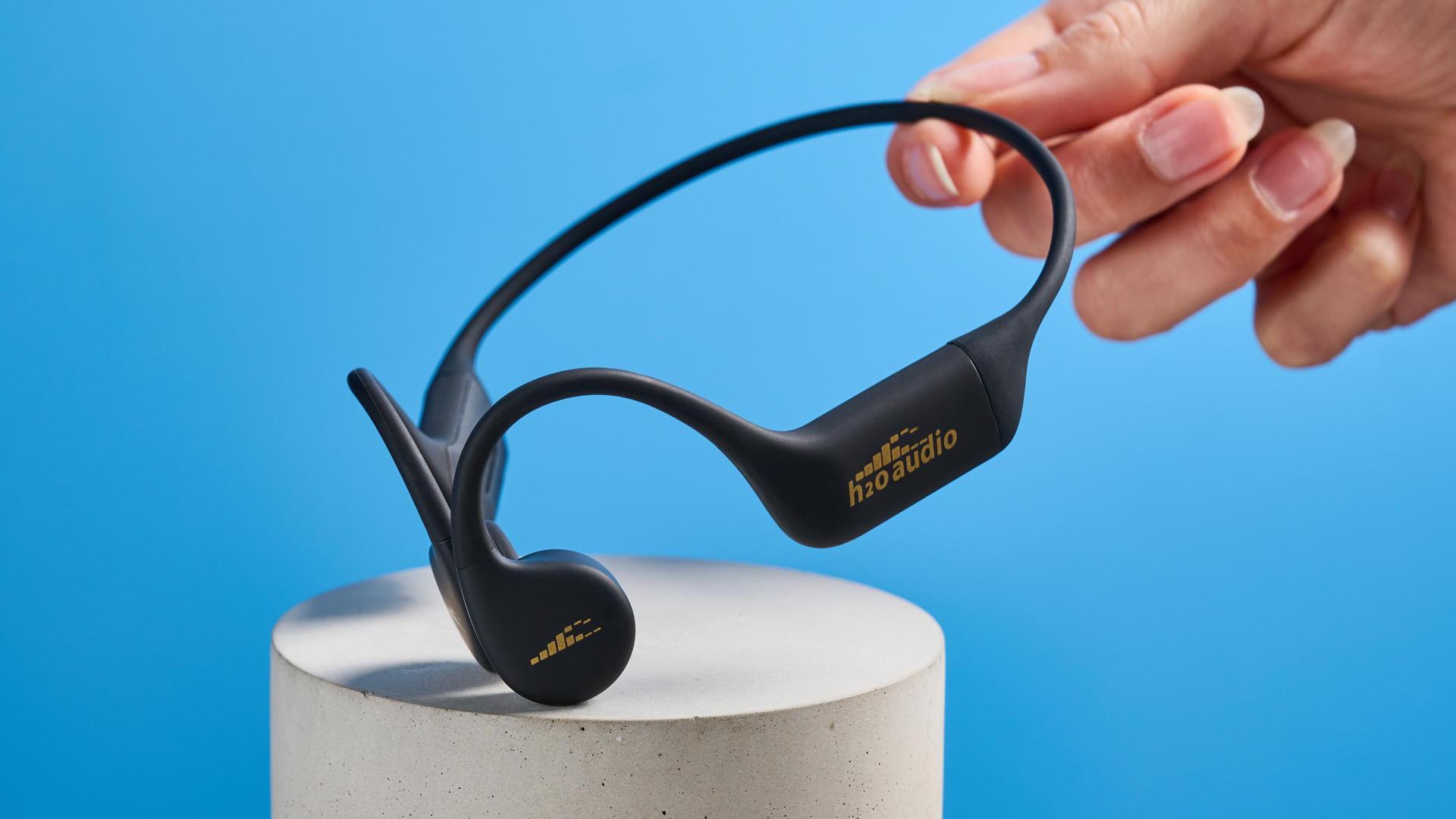 H2O Audio TRI 2 PRO headphones photographed in front of a blue background