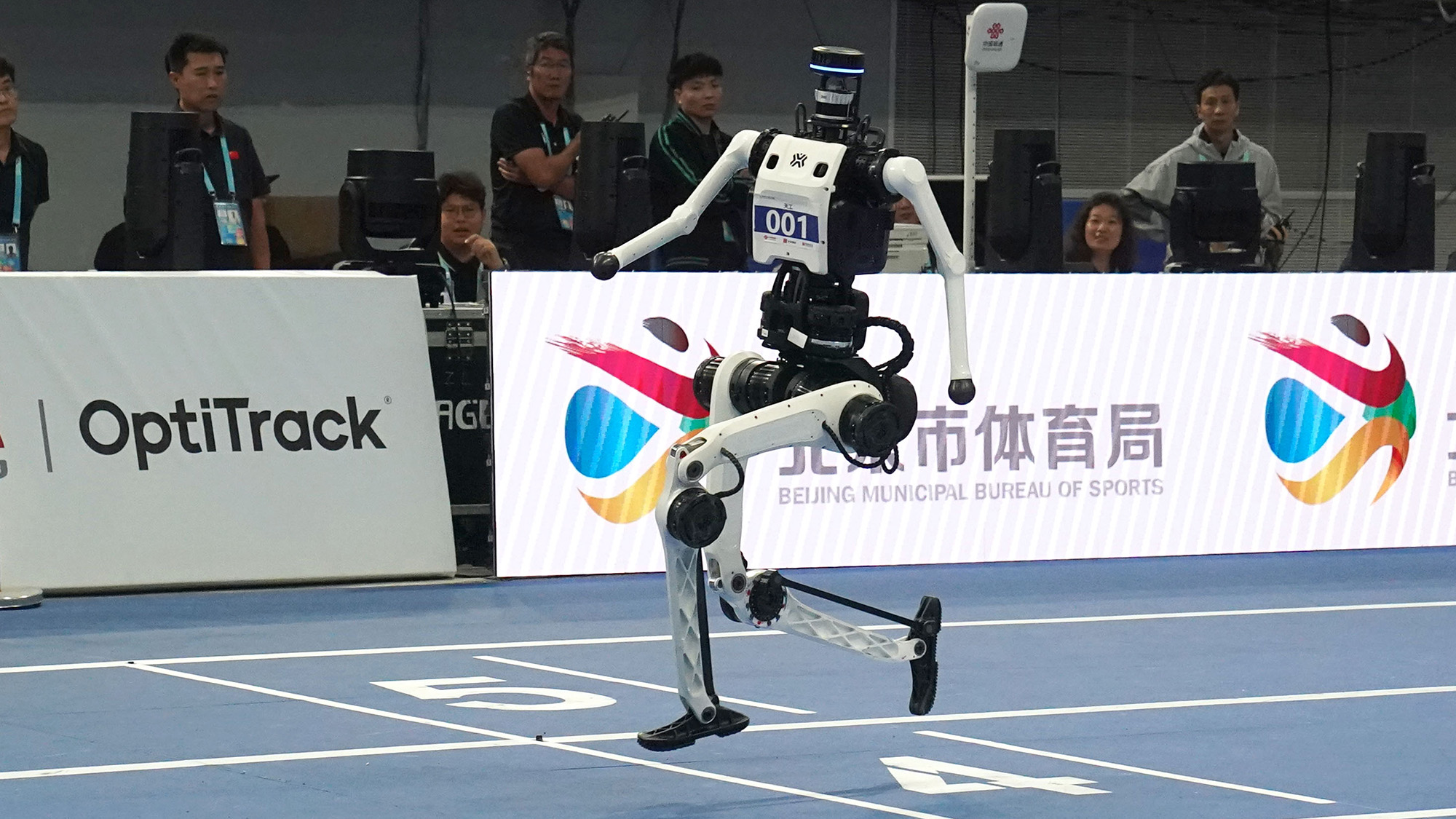 A humanoid robot runs on a blue track