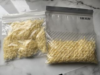 Grated cheese separated into two freezer bags - with one bag showing the cheese laid flat for easy defrosting