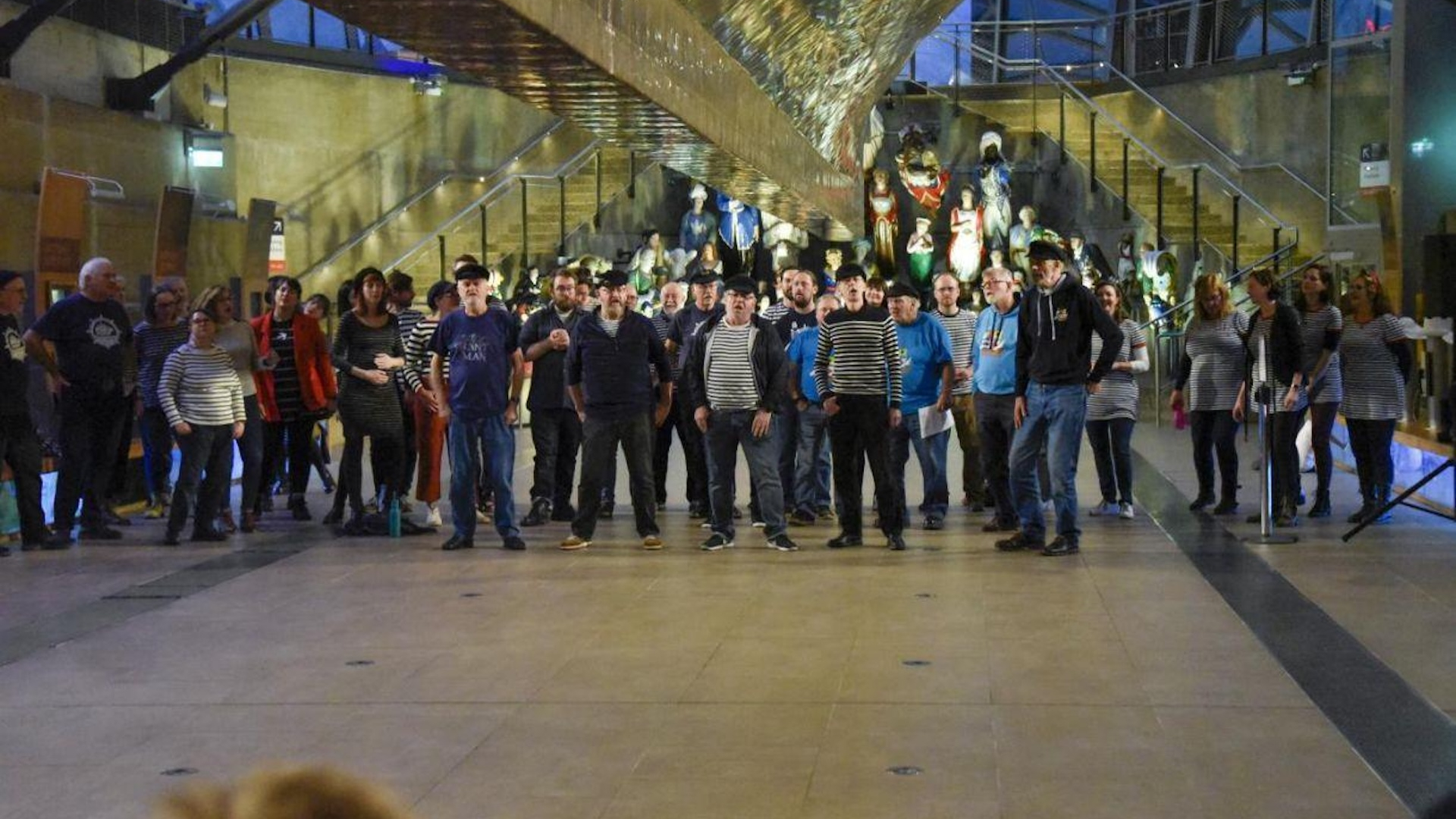 People standing under the Cutty Sark singing at the Sea Shanty Festival