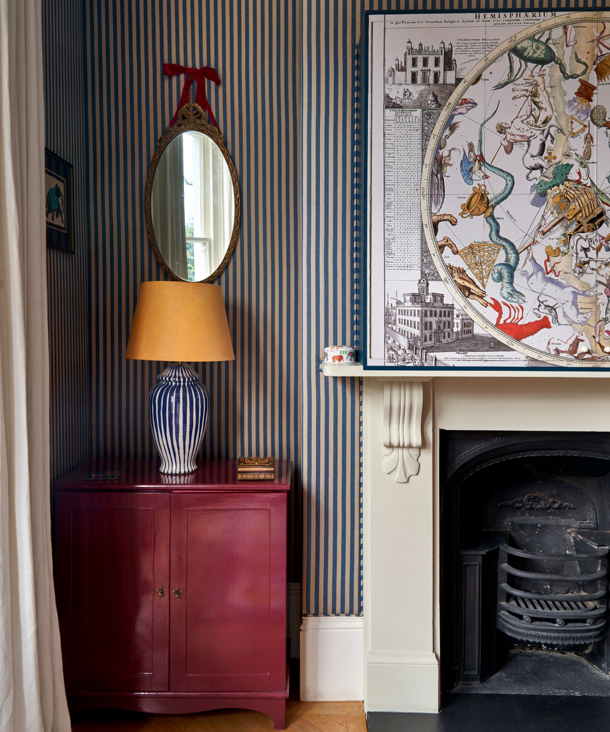 a striped living room with a traditional fireplace and a hidden tv painted with astrology artwork