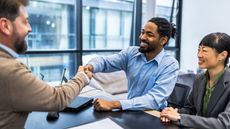 A financial planner shakes hands with a client in the adviser's office.