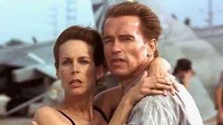Harry and Helen hug each other as they stare at something off-camera in True Lies