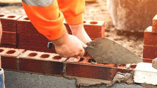 Hand and trowel laying red bricks