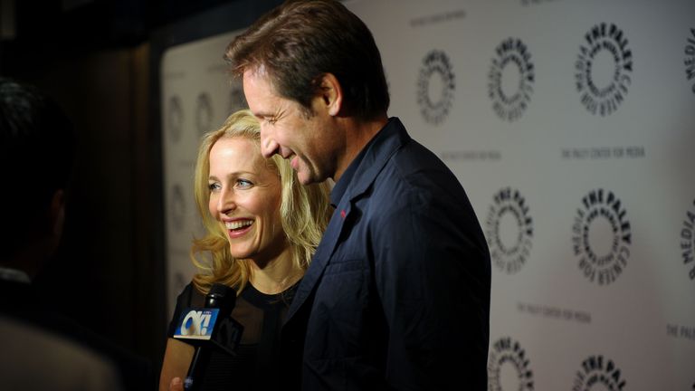 Gillian Anderson and David Duchovny stand together as they are interviewed.