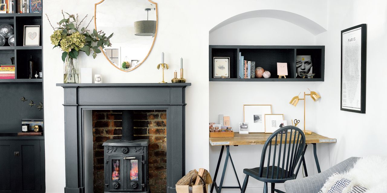 White living room with stove inside black-painted fireplace and home office area tucked into alcove