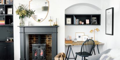 White living room with stove inside black-painted fireplace and home office area tucked into alcove