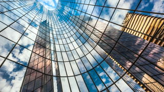 Reflection of blue sky on building glass windows with curve lines.