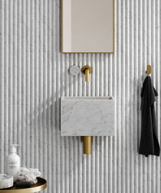 fluted tile wall with small rectangular marble wall mounted sink and tap above