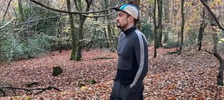 Hiker wearing Icebreaker 260 ZoneKnit Long Sleeve Half Zip Thermal Top in leafy woods