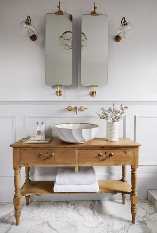 white bathroom with panelling, double mirrors, vintage vanity unit, white basin, wall lights