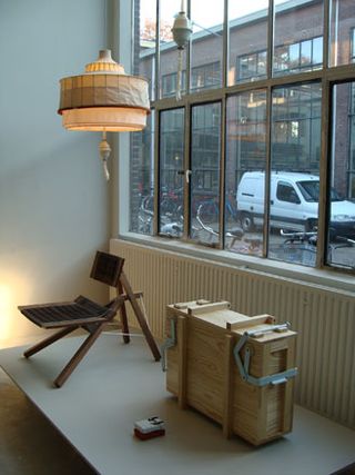 A chair, light, and wooden suitcase in front of a window