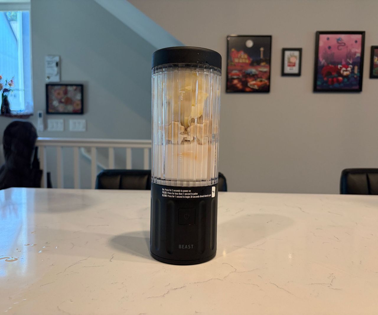 fruit and milk for a smoothie inside a small portable blender with a black base and lid.