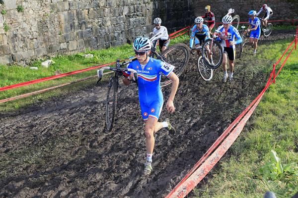Nicolas Samparisi (Italy) shoulders his bike through the mud.