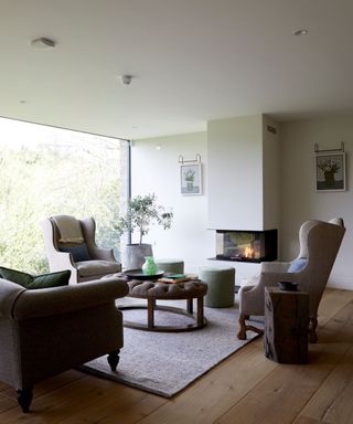 A neutral living room with symmetrical seating and a lit fireplace