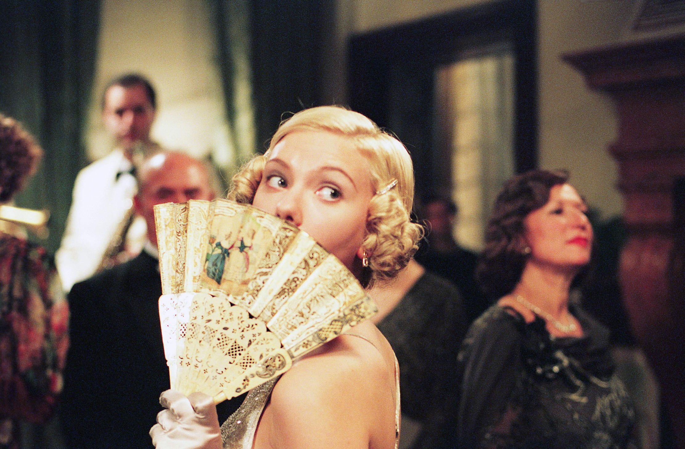 A woman in the 1920s hides her face with a handheld fan