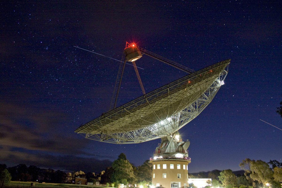 Parkes 64 meter radio telescope with space shuttle Atlantis, International Space Station in the sky behind it.