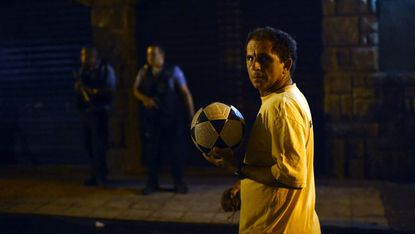 A man walks past armed police officers in a favela near Copacabana beach
