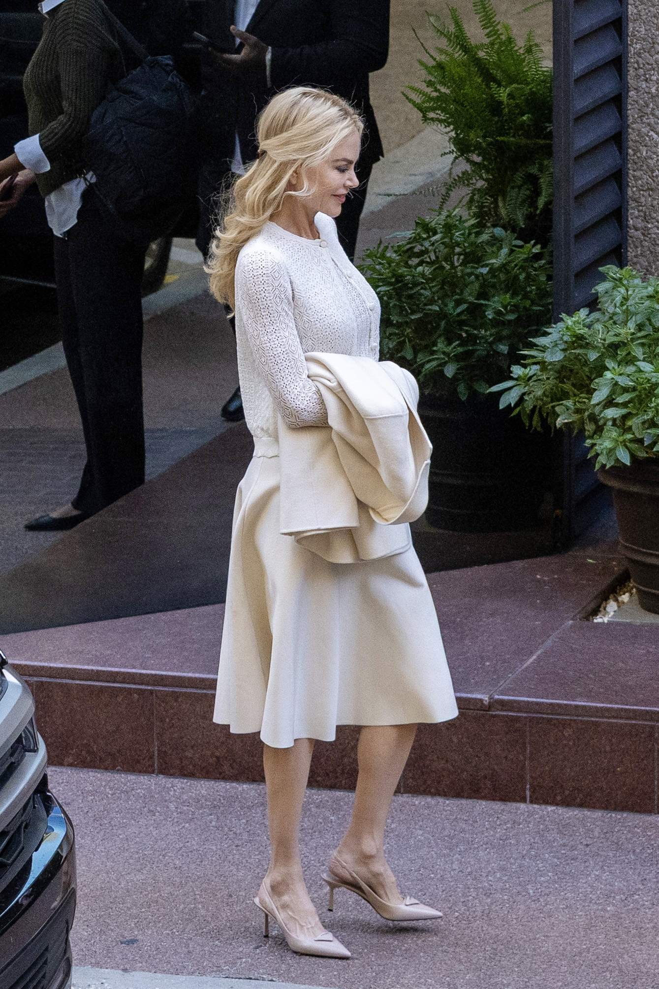 10/29/2025: Nicole Kidman in New Orleans, Louisiana wearing a white cardigan, matching skirt, and Prada heels.