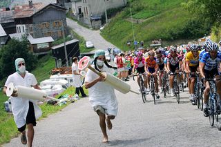 Two men run carrying giant syringes to denounce doping as the pack rides by during the 2005 Tour de France
