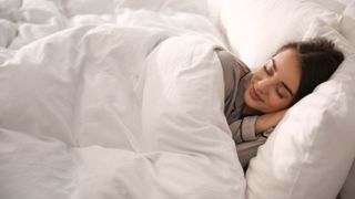 A woman sleeping under a thick duvet