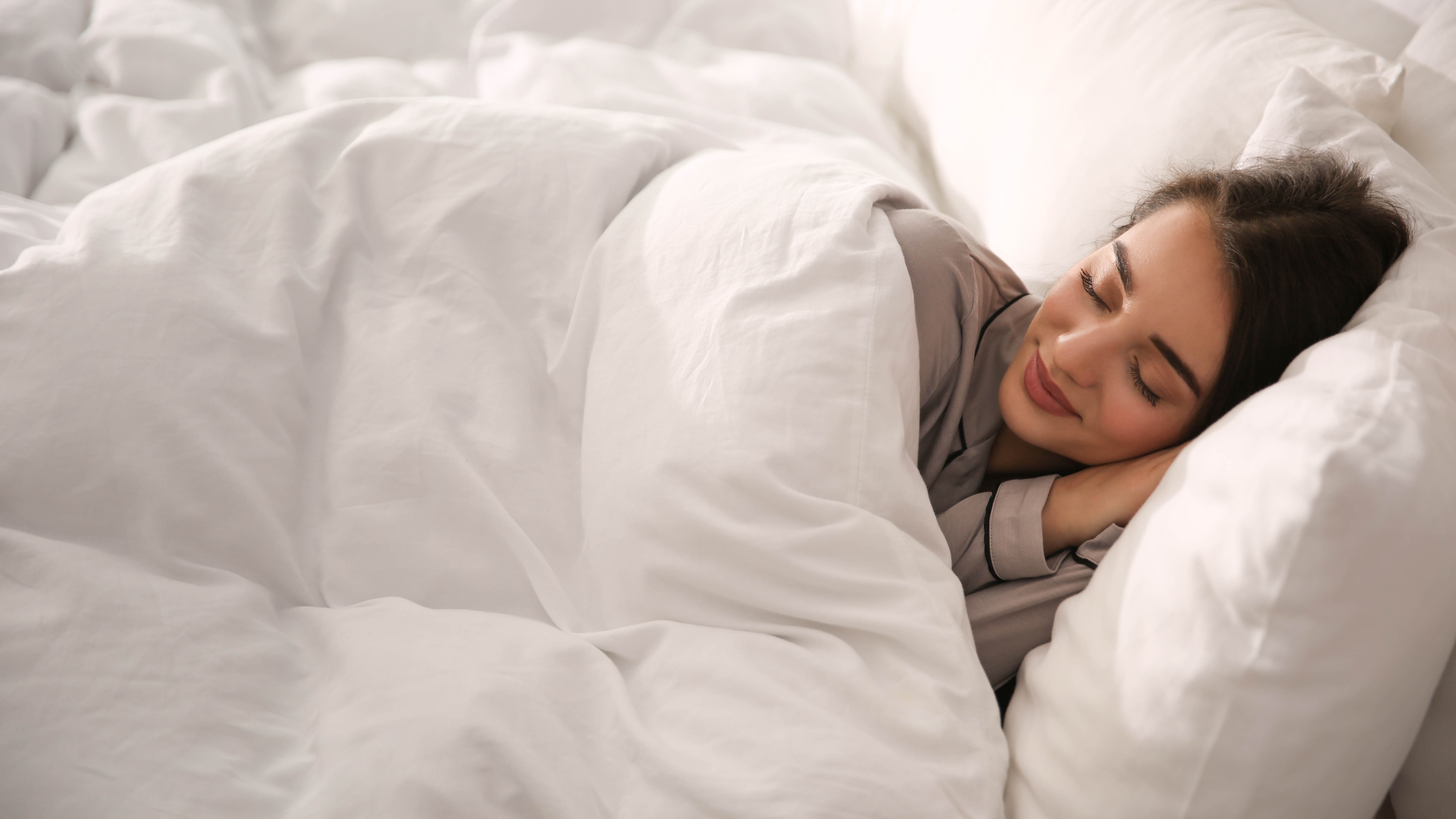 A woman sleeping under a thick duvet