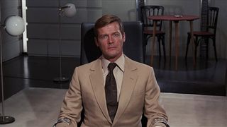 A sharp suited Bond sits in a chair and looks concerned in Live and Let Die