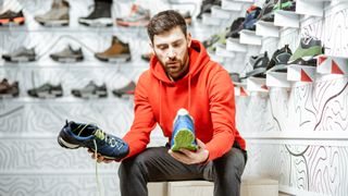 Man in store choosing between two running shoes
