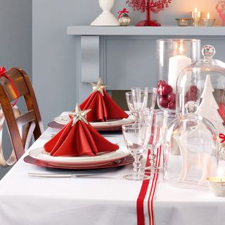 red Christmas napkins folder into trees with gold stars and placed on dinnerware