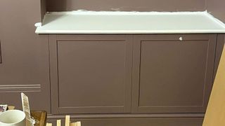 Brown MDF furniture against a brown wall with lime green painted top and tools in the foreground