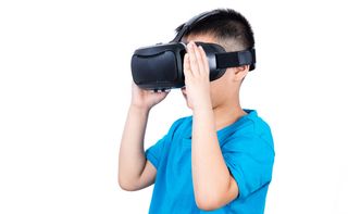 Boy in blue shirt looks through virtual reality goggles