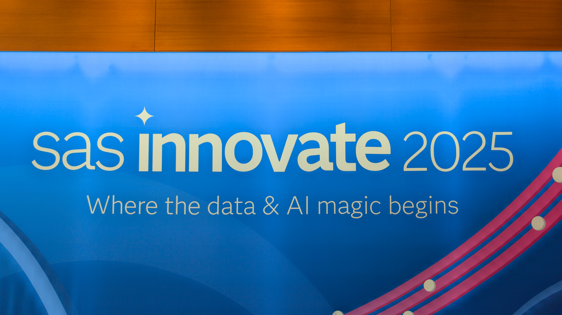 A photo of the SAS Innovate 2025 logo on a billboard at the Hilton Orlando, with the subtitle "Where the data & AI magic begins". The white text is set against a stylized blue background with a pin swipe to the right.