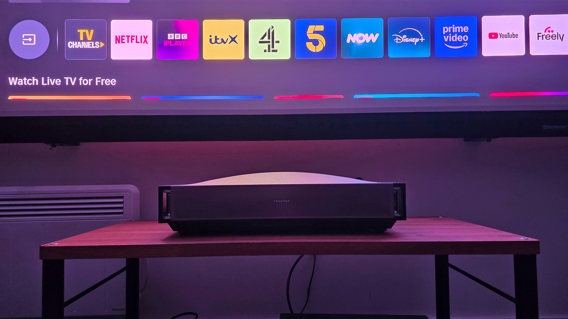 Hisense PX4 Pro UST projector on wooden AV rack, on screen are Tizen apps