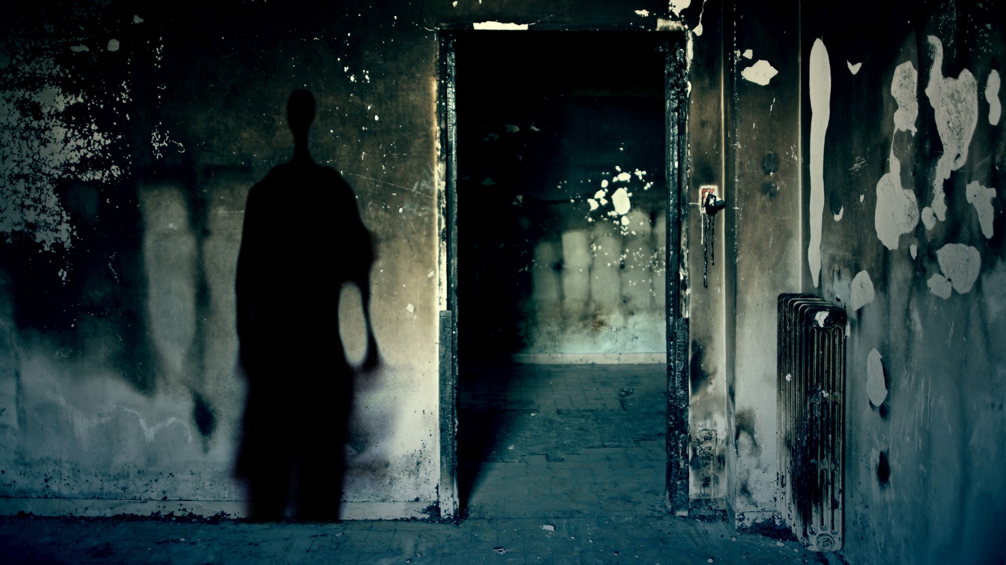 A scary-looking abandoned house with a shadow on the wall.