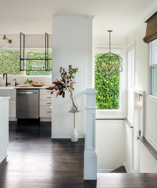 light and airy kitchen with white walls, dark wooden flooring and stairs leading down