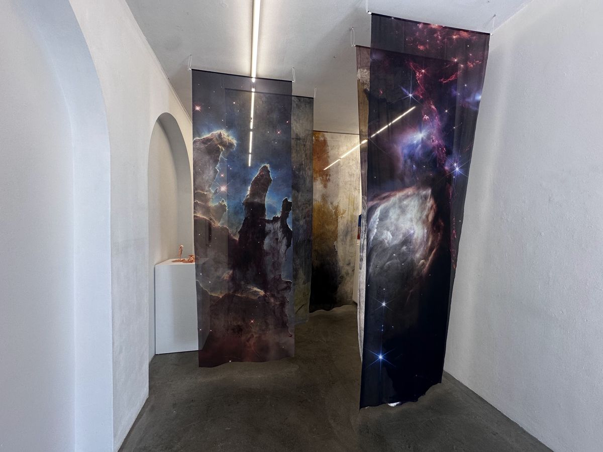 Cloth tapestries of images from the James Webb Space Telescope hang in a narrow white hallway.