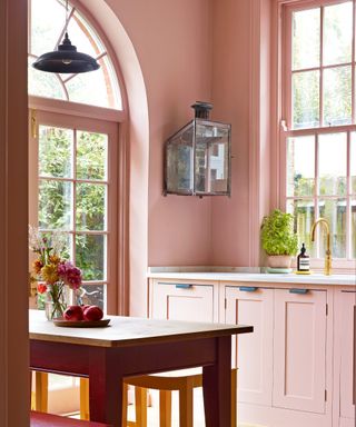 pink kitchen with red table, red bench and gray pendant
