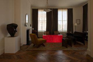 Bright red cuboid in the living room with furniture by Pierre Jeanneret