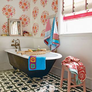 bathroom with floral wall bathtub with towels and designed flooring
