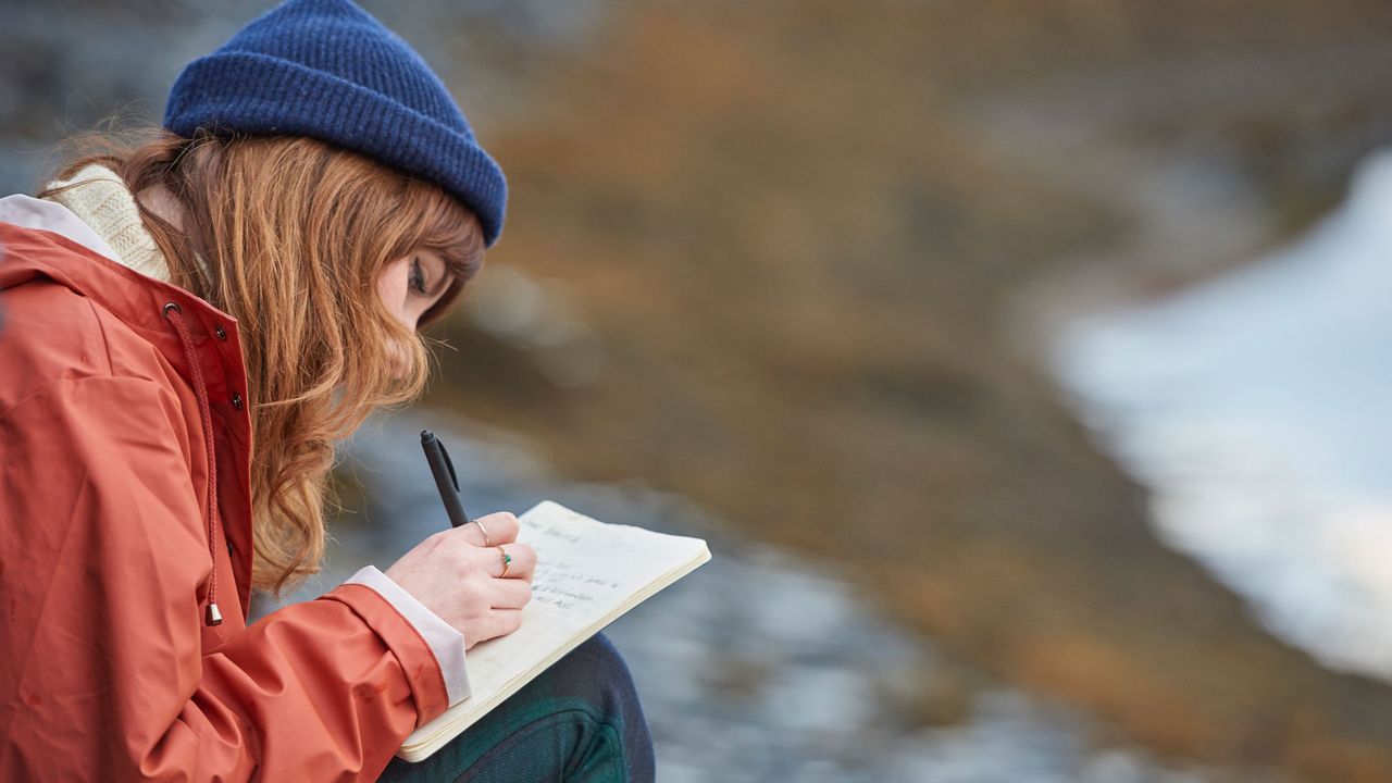 Woman writing in journal on beach
