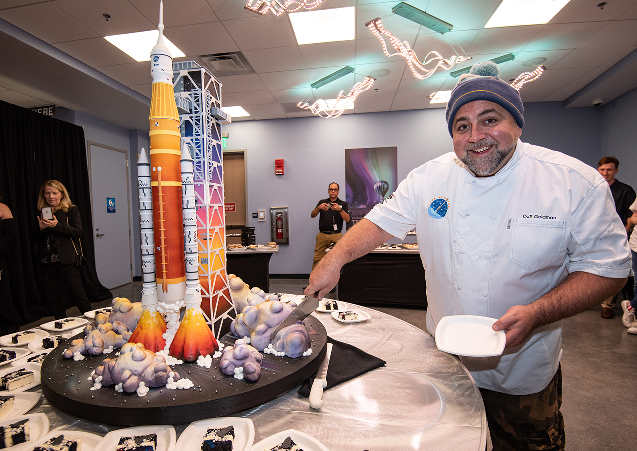 Celebrity chef Duff Goldman cuts into his Space Launch System (SLS)-shaped cake at the Kennedy Space Center Visitor Complex's 