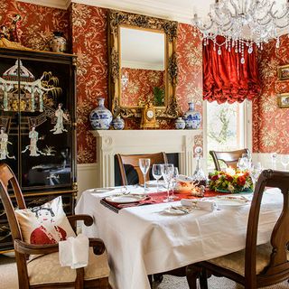 dining room with bold red wallpaper and chandelier