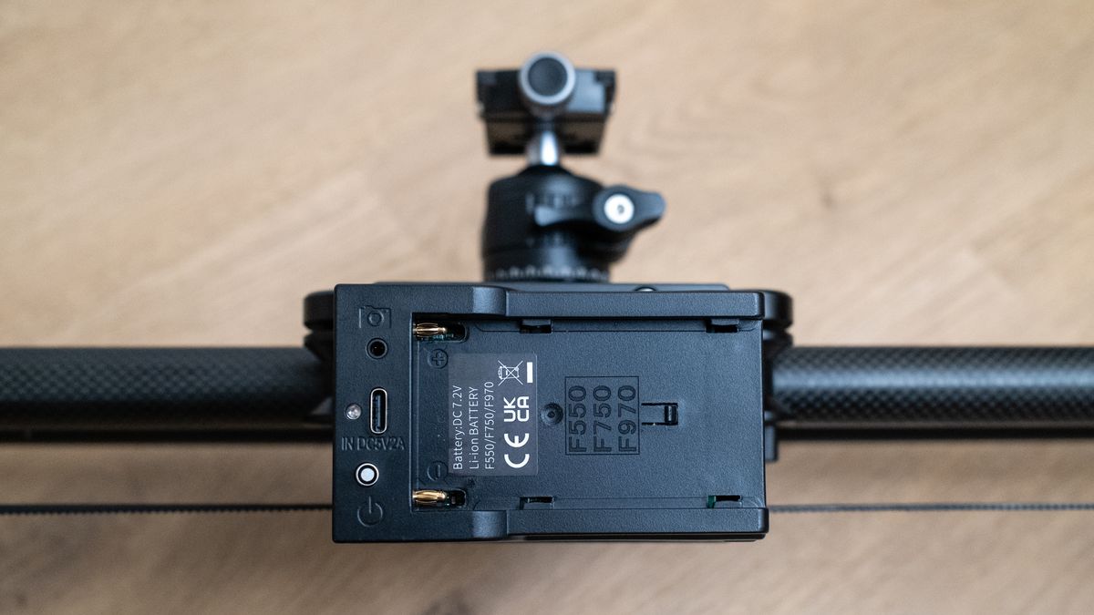 Close up of the battery connection on a Neewer ER1 Motorized Carbon Fiber Camera Slider on a wooden surface