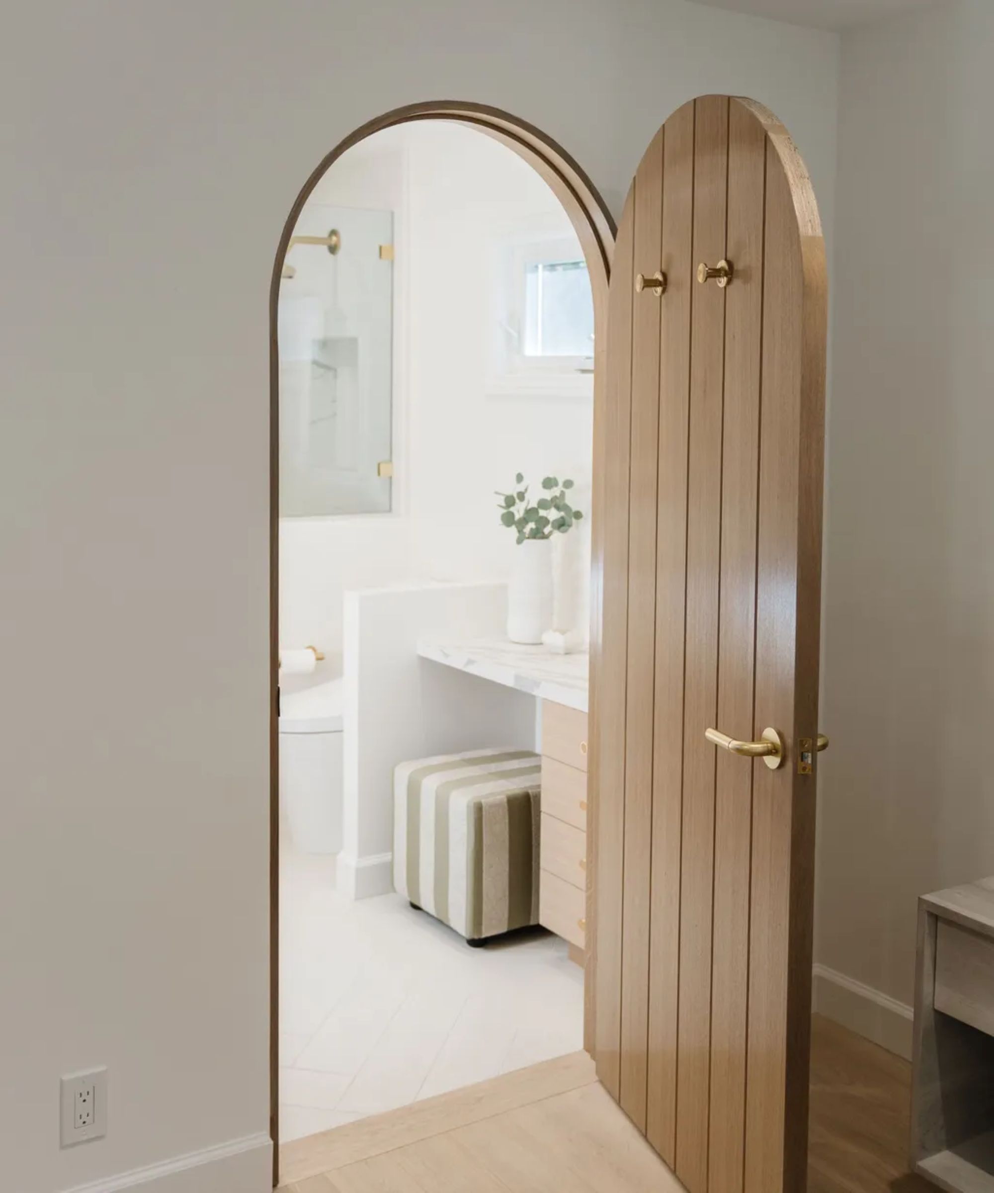 an arched doorway into a white bathroom with a good door knob